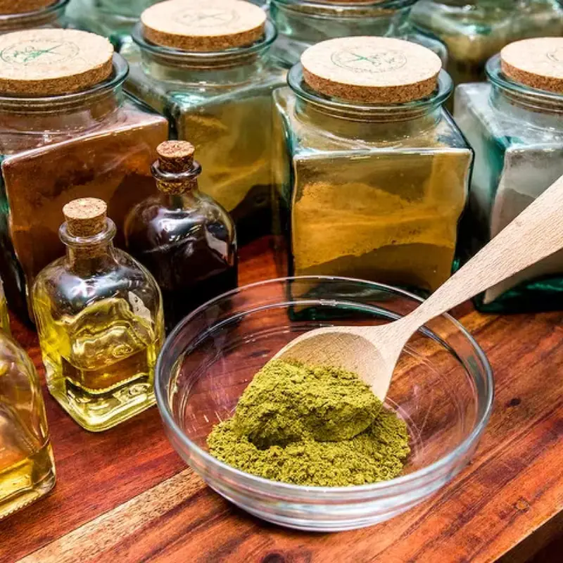 Tarros de polvos vegetales y botellas de aceite, con un cuenco de barro en polvo